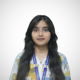 Portrait of a young woman with long dark hair, wearing a patterned blouse and a blue lanyard, against a light gray background.