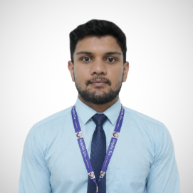 Professional portrait of a man wearing a light blue shirt and dark blue tie, with a purple lanyard around his neck.