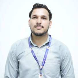 Portrait of a man with short dark hair and a light beard, wearing a light blue shirt and a purple lanyard, looking at the camera.