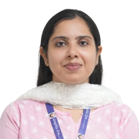 Portrait of a woman with long dark hair in a pink traditional outfit, wearing a blue lanyard with an ID badge, facing the camera.