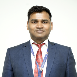 akhilesh-sharma-manegement-hld Professional head-and-shoulders portrait of a man in a navy suit and red tie, wearing a lanyard with a badge.