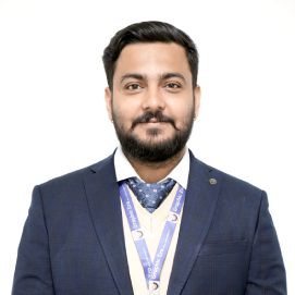 asheesh-csa-hld Portrait of a man in a navy suit with a lanyard, standing against a white background.