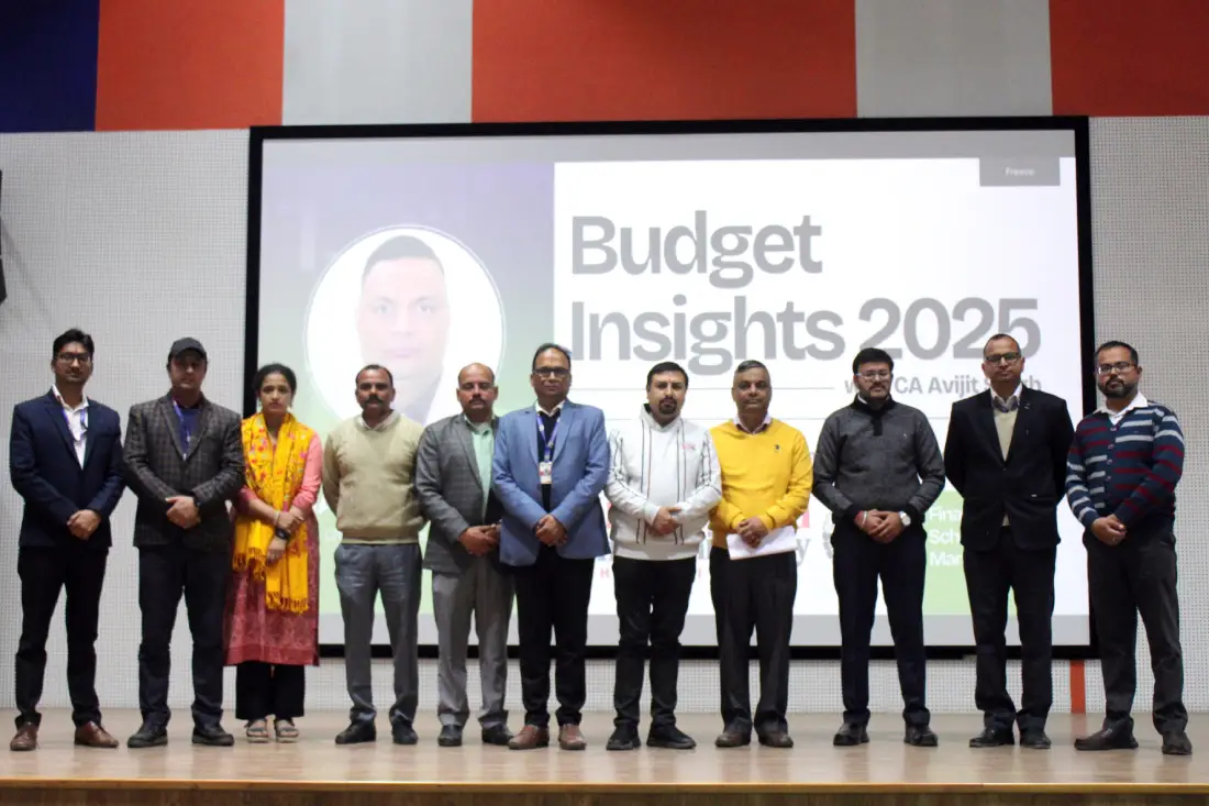 Group of professionals posing on a stage in front of a "Budget Insights 2025" presentation slide for a conference event.