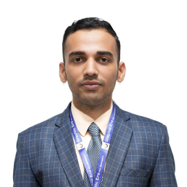 dinak-management-hld Professional man in a blue plaid suit and tie, wearing a conference lanyard.
