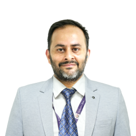 gaurav-joshi-management-hld Portrait of a man with a beard in a light gray suit and blue patterned tie, looking at the camera.