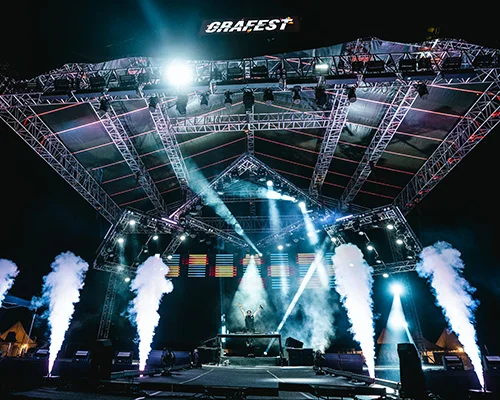 Stage at GraFest with metal truss structure, bright spotlights, and smoky fog surrounding a DJ booth