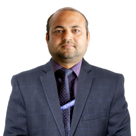 ishwari-cse-hld Professional head-and-shoulders portrait of a man in a navy checkered suit, purple shirt, and dotted tie against a white background.