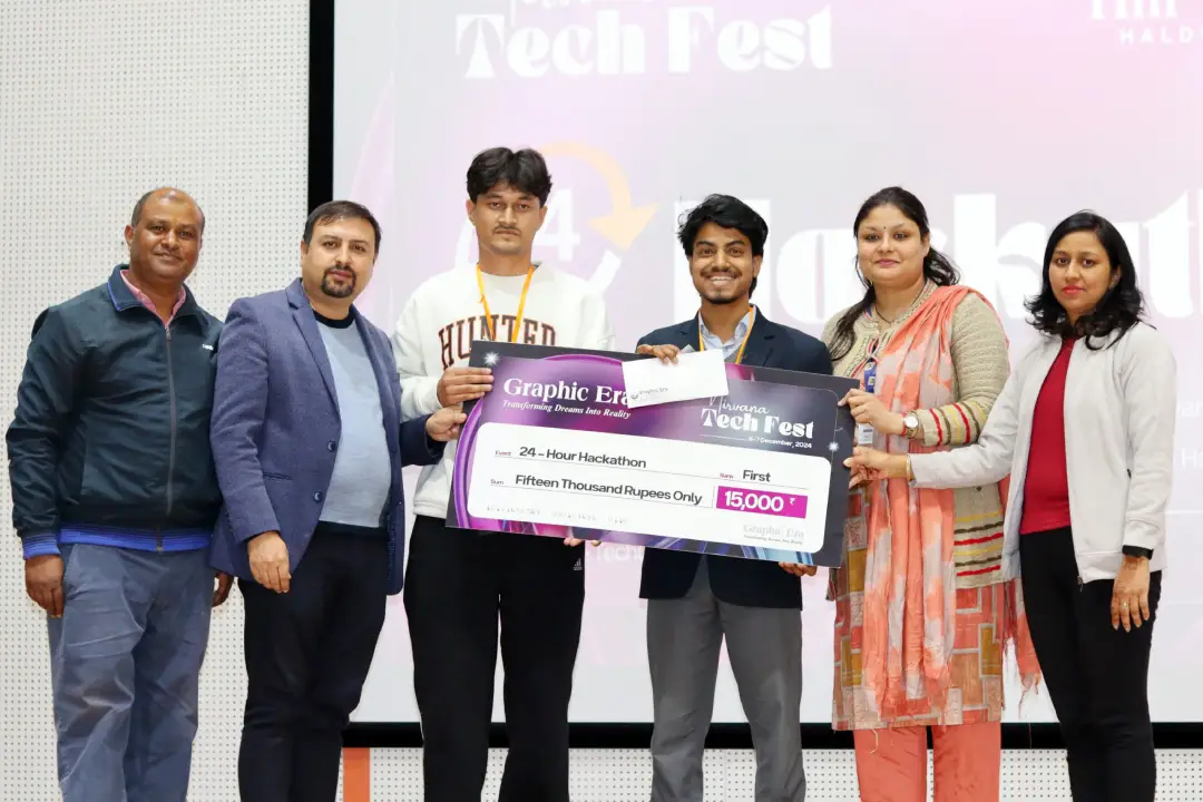 Six people stand on a stage holding a large prize cheque, celebrating a Hackathon win at a Tech Fest event.