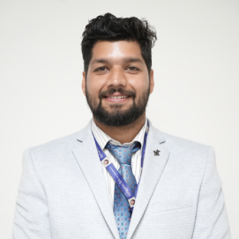 ravi-papnai-management-hld Smiling man with dark hair and a beard in a light gray suit and blue tie, wearing a conference lanyard.